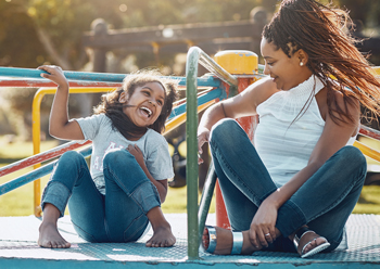 Equipment-Financing mom and daughter playing on carousel at playground